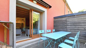 Un patio al aire libre con una mesa y sillas, cerca de una valla de madera y la entrada de un edificio.