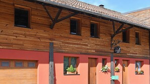 Un edificio de madera con fachada roja, múltiples ventanas y puerta de madera.