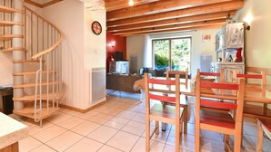 Una cocina con una escalera de madera, un comedor con sillas de madera y vistas al exterior a través de un gran ventanal.