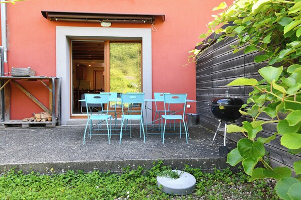 Ein Außenbereich mit Tisch und Stühlen, einem Grill und einem Blumentopf.