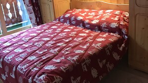 Um quarto de madeira com uma cama, uma janela com cortinas e uma cabeceira de madeira.