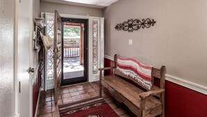 A hallway with a wooden bench, a patterned rug, and a decorative wall piece.
