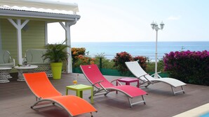 A poolside area with four lounge chairs, a small table with a drink, and a potted plant.