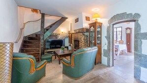 A cozy living room with a fireplace, a television, and green leather chairs.