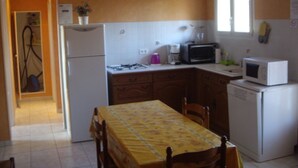 Cozinha compacta com geladeira, micro-ondas, fogão e mesa de jantar com cadeiras.
