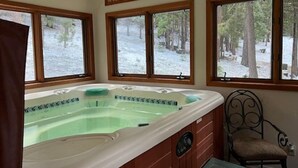Uma banheira de hidromassagem em um quarto com paredes de madeira e grandes janelas.