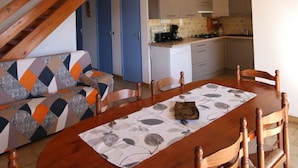 Un comedor con una mesa y sillas de madera, un camino de mesa estampado y un ventilador de techo.
