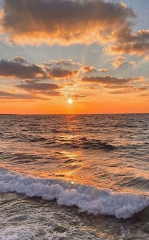Solnedgang over havet med bølger.