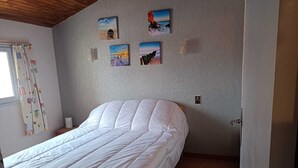 Un dormitorio con una cama grande, techo de madera y cuatro cuadros en la pared.