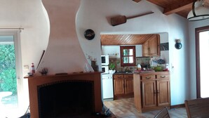 A kitchen with wooden cabinets, a stove, and a dining area with a table and chairs. - Very quiet location, 5 minutes from the beach/10 minutes from shops by bike, large garden with castle view/Wifi. (Noirmoutier-En-L'île)