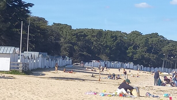A sandy beach with people sunbathing and walking. There are wooden structures along the beach, possibly for beachgoers to use. - Very quiet location, 5 minutes from the beach/10 minutes from shops by bike, large garden with castle view/Wifi. (Noirmoutier-En-L'île)