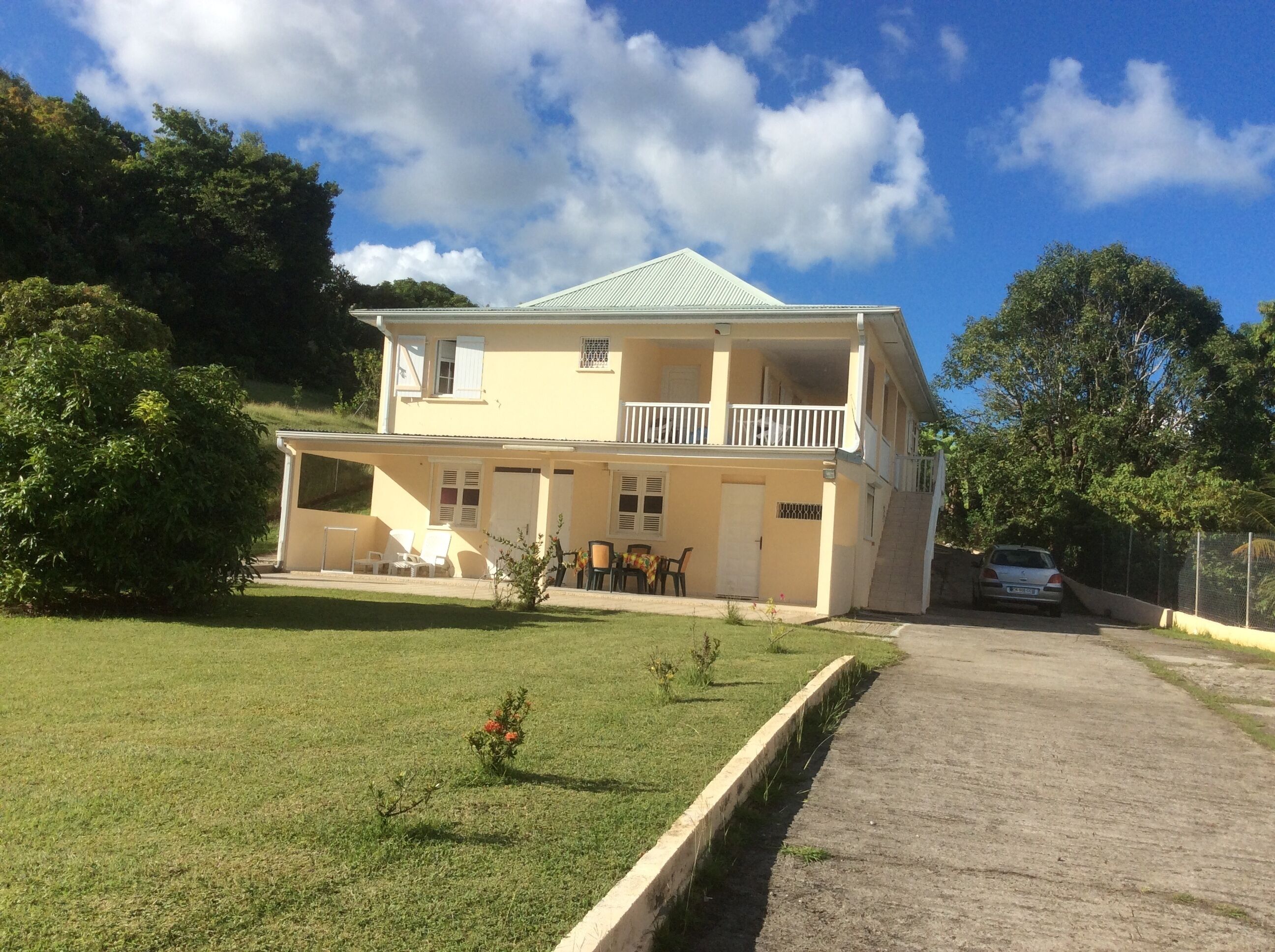 Une maison à deux étages avec un balcon, une allée pavée et une pelouse.