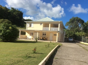 Une maison à deux étages avec un balcon, une allée pavée et une pelouse.