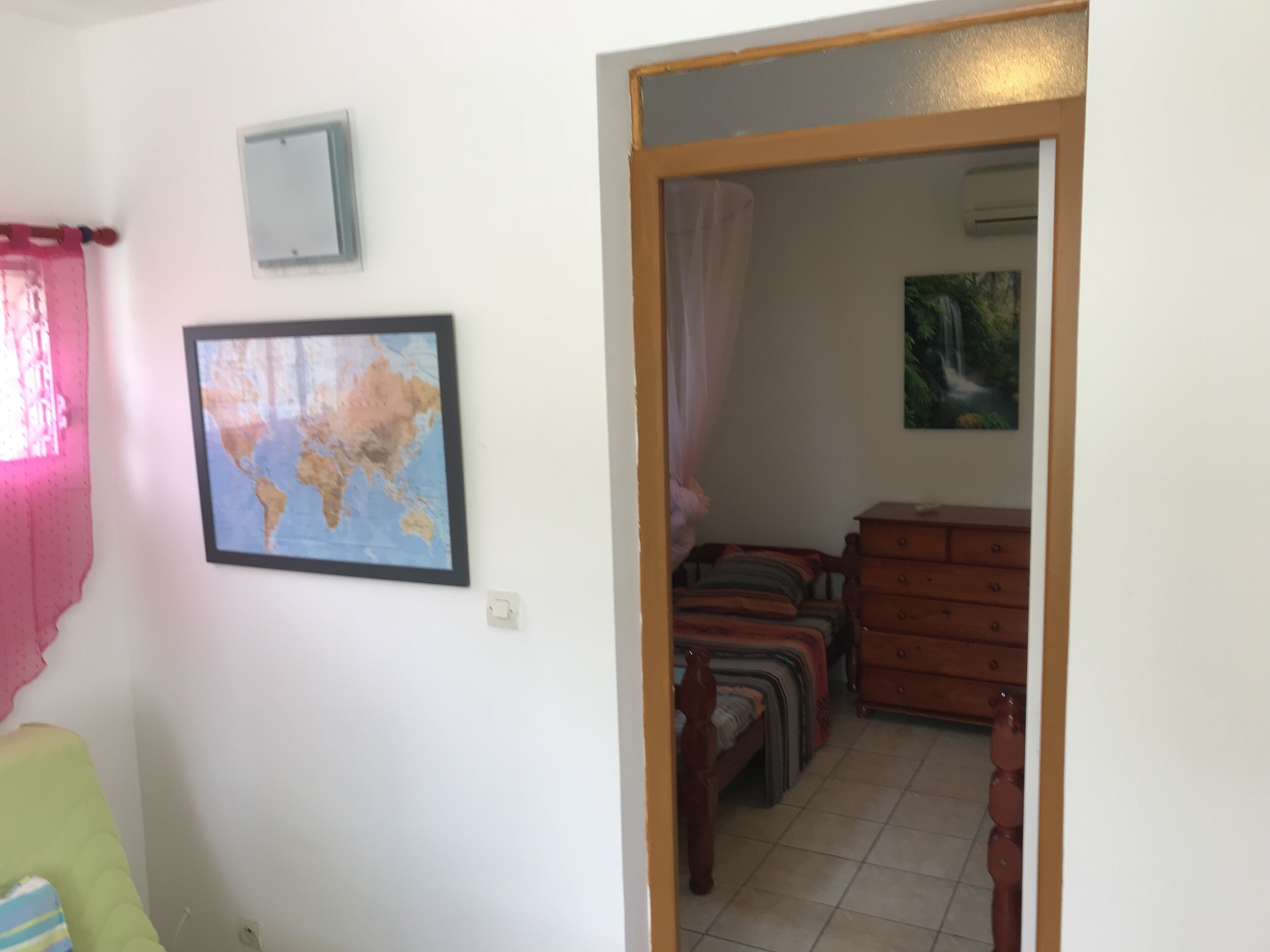 Une pièce avec un lit, une commode, une carte accrochée au mur et un tableau.