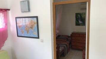Une pièce avec un lit, une commode, une carte accrochée au mur et un tableau.