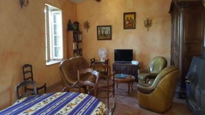 A cozy living room with a bed, two armchairs, a small table, a television, and a fireplace. - Independent MAS in the middle of vineyards in St Pons de Mauchiens, 10 km from Pézenas (Saint-Pons-De-Mauchiens)
