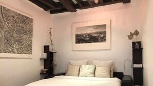 A bedroom with a bed, a map, and a framed cityscape. - Charming studio Ile Saint Louis PARIS 4 ° ° - Paris (Paris)