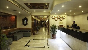 A hotel lobby with a reception desk, seating area, and a long corridor with doors. - Sunfort hotel (Lahore)