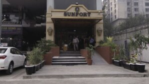A building with a sign reading "SUNPORT" at the entrance. There are steps leading up to the entrance, and potted plants are placed on either side. - Sunfort hotel (Lahore)