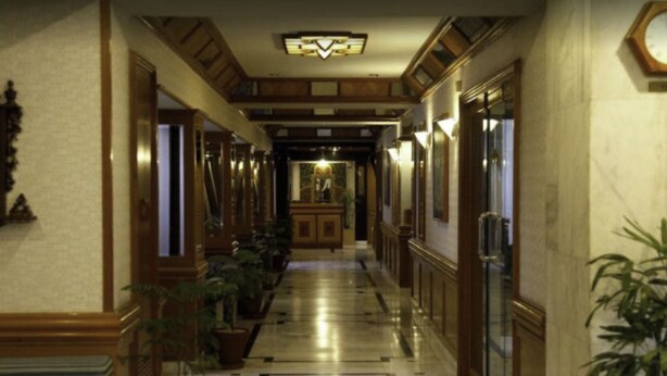 A hotel hallway with wooden paneling, potted plants, and a chandelier. - Sunfort hotel (Lahore)