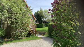A garden pathway leading to a building with a sloped roof and wooden staircase.