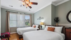 A hotel room with two beds, a ceiling fan, a window with curtains, a nightstand with a lamp, and a decorative wall piece. - 1.0 mile to Broadway, 1.2mi Topgolf, 1.4mi Music City Center, 2.4mi Vanderbilt (Nashville)