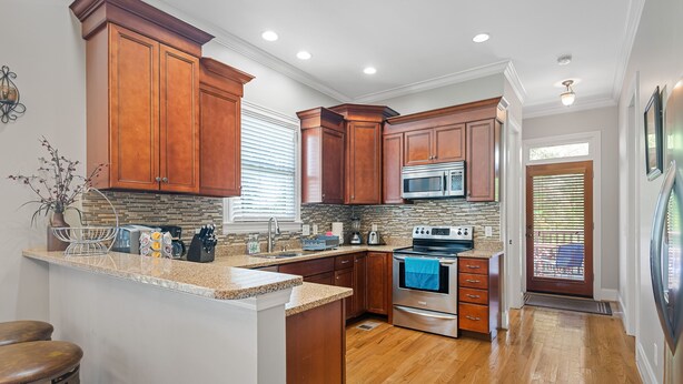 A kitchen with wooden cabinets, a granite countertop, stainless steel appliances, and a built-in island. - 1.0 mile to Broadway, 1.2mi Topgolf, 1.4mi Music City Center, 2.4mi Vanderbilt (Nashville)