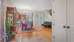 A spacious living area with a dining table, chairs, a red rug, and a black leather sofa. - 1.0 mile to Broadway, 1.2mi Topgolf, 1.4mi Music City Center, 2.4mi Vanderbilt (Nashville)