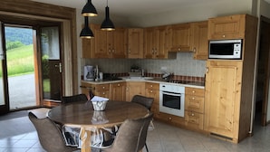 Eine moderne Küche mit Holzausstattung, einem eingebauten Ofen, einer Mikrowelle und einem Essbereich mit Tisch und Stühlen.