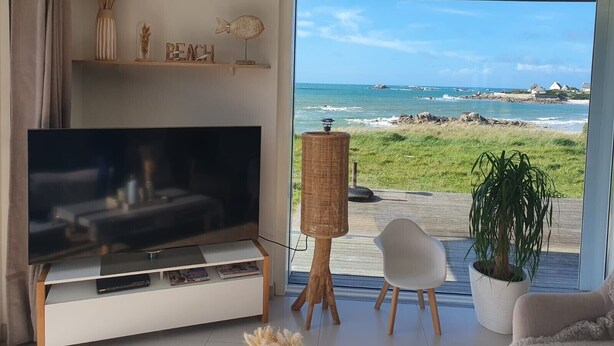 A modern living room with a large TV, wicker furniture, and a view of the beach. - Villa des Courlis, 10 people, beach at your feet (Kerlouan)