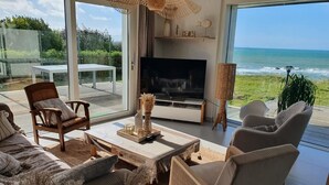 A modern living room with a large TV, comfortable seating, and a view of the ocean. - Villa des Courlis, 10 people, beach at your feet (Kerlouan)