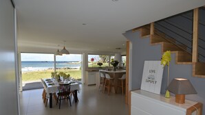 A modern kitchen with a view of the beach, a dining area with a table set for four, and a staircase with a 'Live Simply' sign. - Villa des Courlis, 10 people, beach at your feet (Kerlouan)