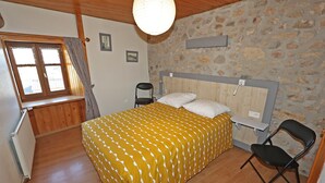 Ein Schlafzimmer mit einem Bett, einem Stuhl, einem Fenster und einer Steinwand.