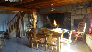 Ein gemütlicher Essbereich mit Kamin aus Stein, Holzmöbeln und einer Treppe zu einer weiteren Ebene.