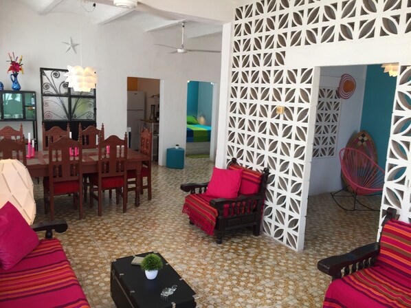 A living room with a dining area, a white partition, and a ceiling fan.