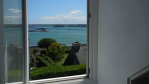 Vista desde una ventana sobre aguas tranquilas, una isla distante y cielo despejado.