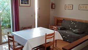 Een kamer met een eettafel, stoelen, een bank en een plafondventilator.