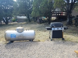A portable gas tank and a barbecue grill in an outdoor setting. - The Pines at Mayhill (Mayhill)