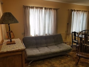 Ein Wohnzimmer mit Sofa, Lampe und Vorhängen.