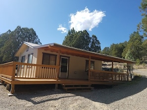A two-story wooden cabin with a porch, a door, and a window. - The Pines at Mayhill (Mayhill)