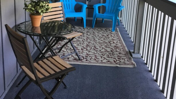 Uma área de estar coberta ao ar livre, com mesa, cadeiras e um vaso de planta.