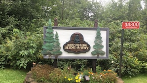 Placa para Brookside Hide-A-Way, com moldura de pedra e poste de madeira.