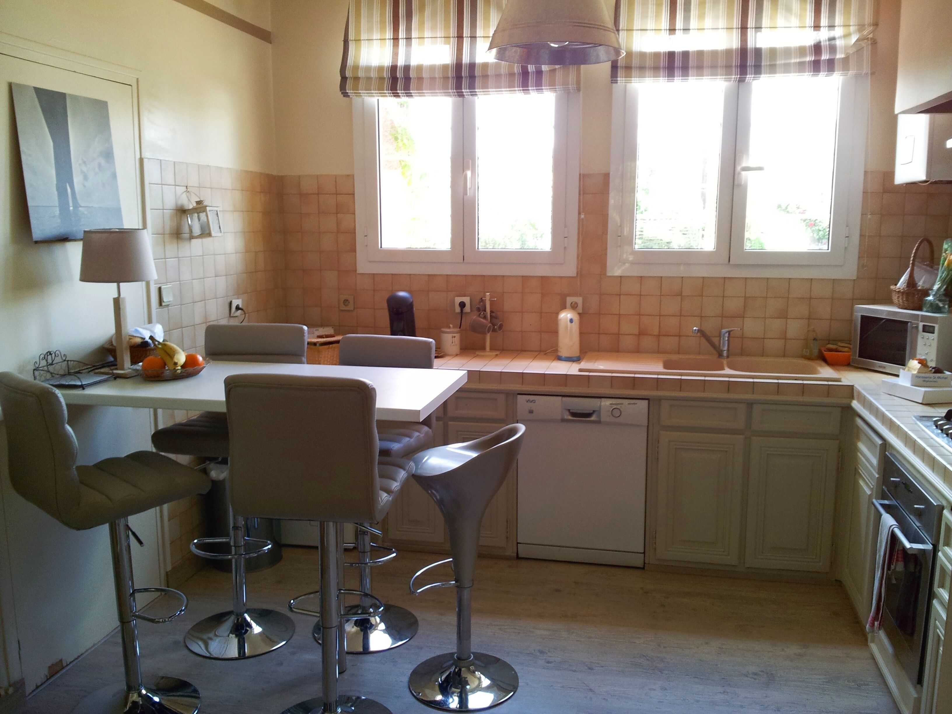Une cuisine comprenant un coin repas, avec une table, des chaises, un évier et un lave-vaisselle.