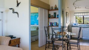Une pièce comprenant un lit, une table à manger avec des chaises, un ventilateur de plafond et un coin cuisine équipé d’un four à micro-ondes.