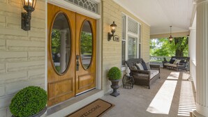 A porch with a double door, a welcome mat, and outdoor furniture. - Amazing Home & Area - Close to Downtown Nashville! Family & Group Friendly! (Nashville)