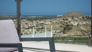Un balcón con vistas a un pueblo costero, que incluye casas y una colina.