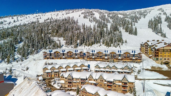 A snow-covered lodge with multiple floors, ski lifts, and a ski slope in the background.