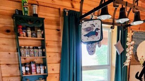 A wooden cabin kitchen with a coffee maker, a shelf with spices, and a window with curtains. - Elk Ridge cabin with great views near Yellowstone (Livingston)