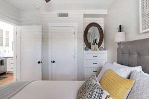 Une chambre à coucher avec un lit, une commode, un miroir et une lampe.