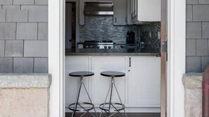 A modern kitchen with white cabinets, a stainless steel stove, and two bar stools. - Playa One Bedroom (253) (Carpinteria)